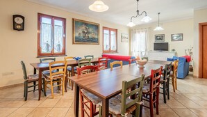 A dining area with a wooden table and chairs, a painting, and a television in the background. - Holiday Home 'Podere Calistri' with Mountain View, Wi-Fi and Air Conditioning (Larciano)