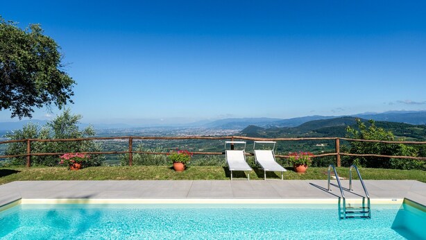 A swimming pool with two lounge chairs and a wooden fence overlooking a scenic landscape. - Holiday Home 'Podere Calistri' with Mountain View, Wi-Fi and Air Conditioning (Larciano)