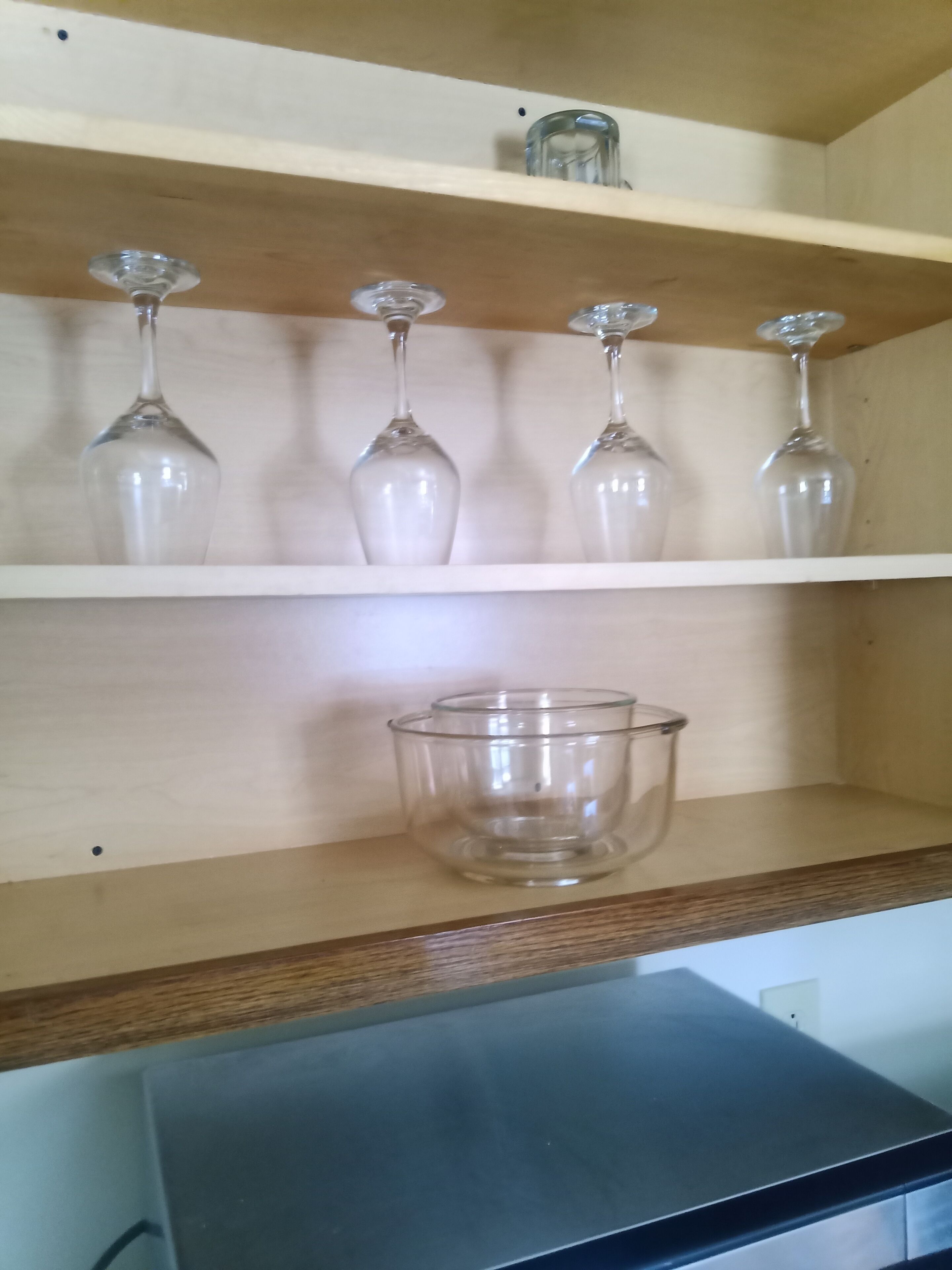 Een houten plank met vier wijnglazen en een transparante glazen schaal.