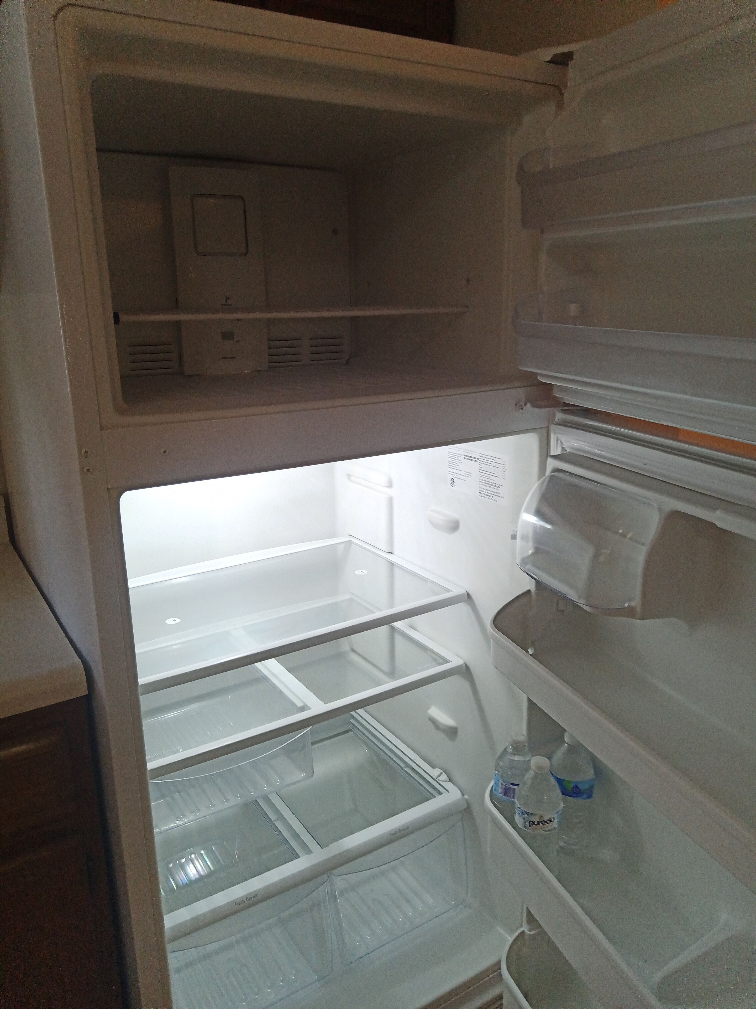 An open refrigerator with multiple shelves and a water dispenser.