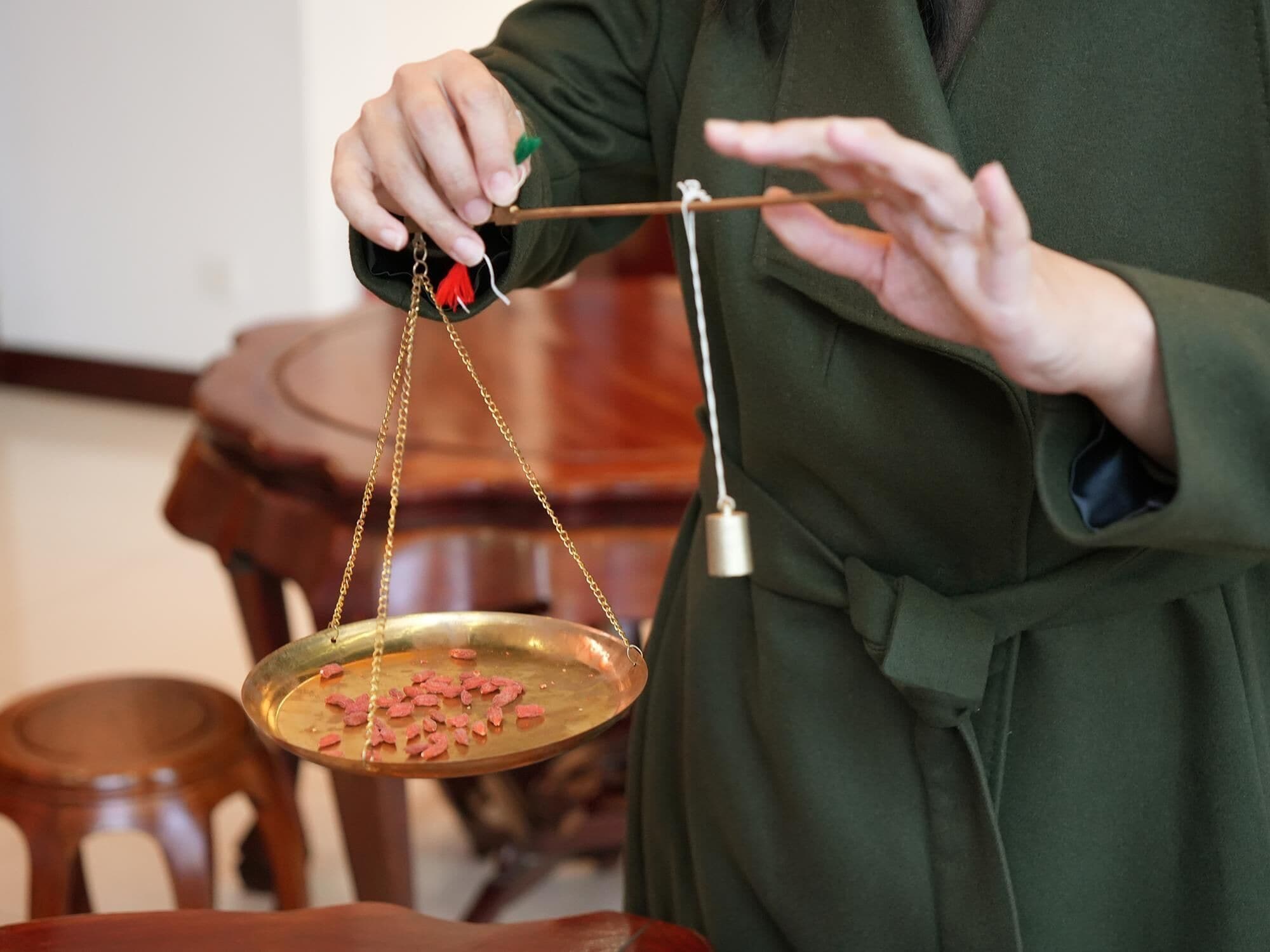 A person holding a balance scale with a tray of pink objects.