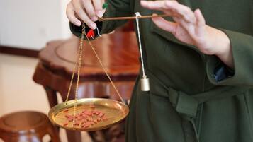 A person holding a balance scale with a tray of pink objects.