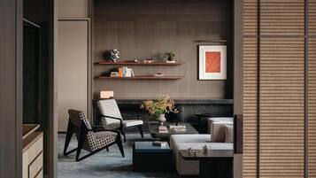 Una sala de estar moderna con sofá, sillón, mesa de centro y estanterías con libros y objetos decorativos.
