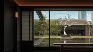 Un intérieur moderne avec une grande fenêtre, un banc et une sculpture minimaliste.