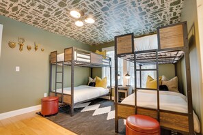 A bunk bed room with a patterned ceiling, a small desk, and a window. - Luxe Mountain Escape ~ Sauna ~ Hot Tub ~ Pool Table ~Arcade Games~ Massage Chair (Bartlett)