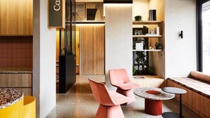 Una cafetería moderna con detalles de madera, zonas de estar y un letrero que dice 'Cafe'.