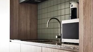 Una cocina moderna con armarios de madera, un lavamanos de acero inoxidable y un microondas.