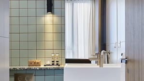 Un baño moderno con salpicadero de azulejos, un lavabo, un espejo y zona de ducha.