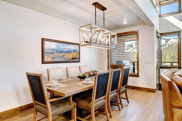 A dining area with a wooden table, chairs, and a hanging light fixture.