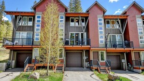 A multi-story residential building with balconies, a garage, and a small tree in front.
