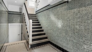 Una escalera con barandilla, una puerta al final e paredes con azulejos.