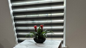 A dining area with a white marble table, a dark green chair, and a potted plant with red flowers. - Cozy Guest Studio with private entrance close to the Heights & TMC (Houston)