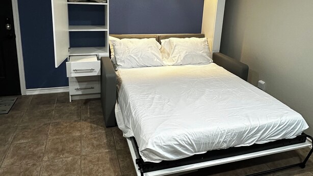 A modern bedroom with a bed, a built-in wardrobe, and a ceiling light. - Cozy Guest Studio with private entrance close to the Heights & TMC (Houston)