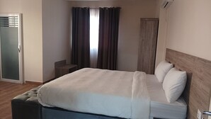 Een moderne hotelkamer met een groot bed, een nachtkastje, een kledingkast en een schuifglazen deur.