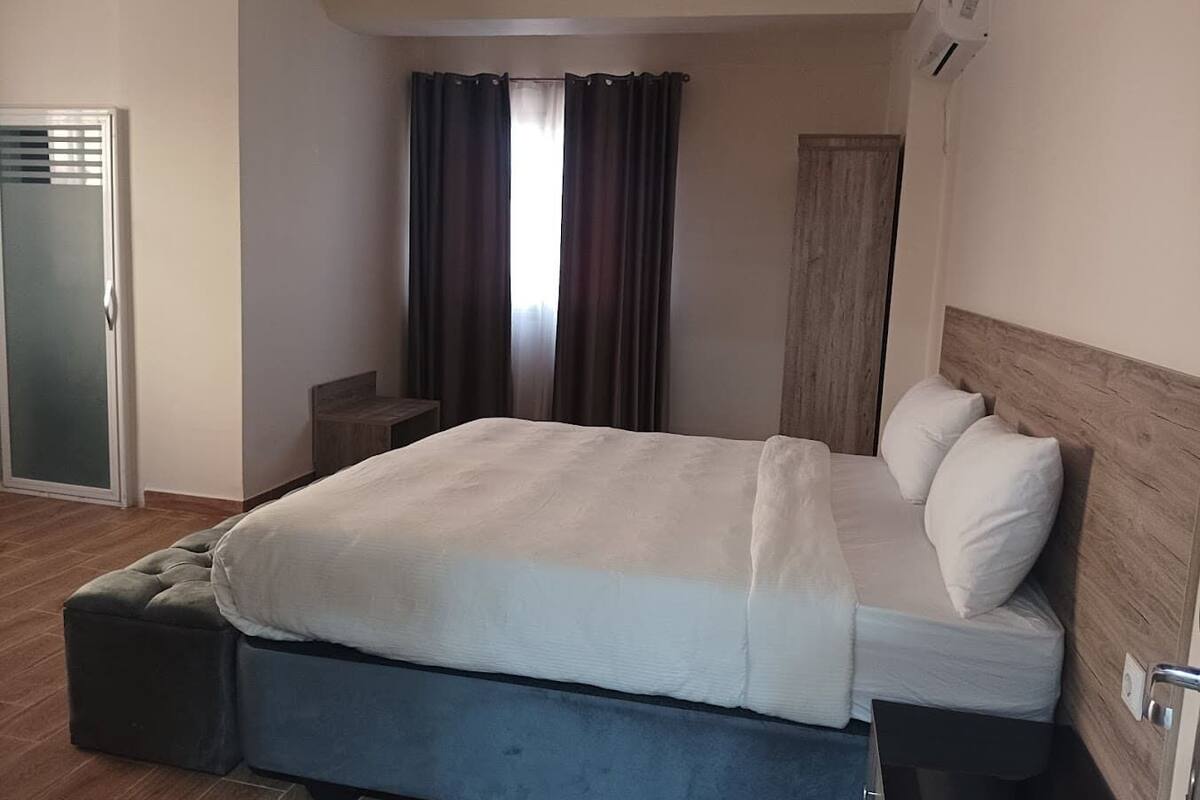 Ein modernes Hotelzimmer mit einem großen Bett, einem Nachttisch, einem Kleiderschrank und einer Schiebetür.