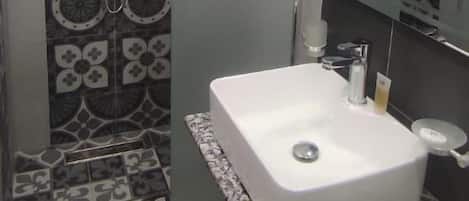 Un baño con ducha, lavabo y espejo.