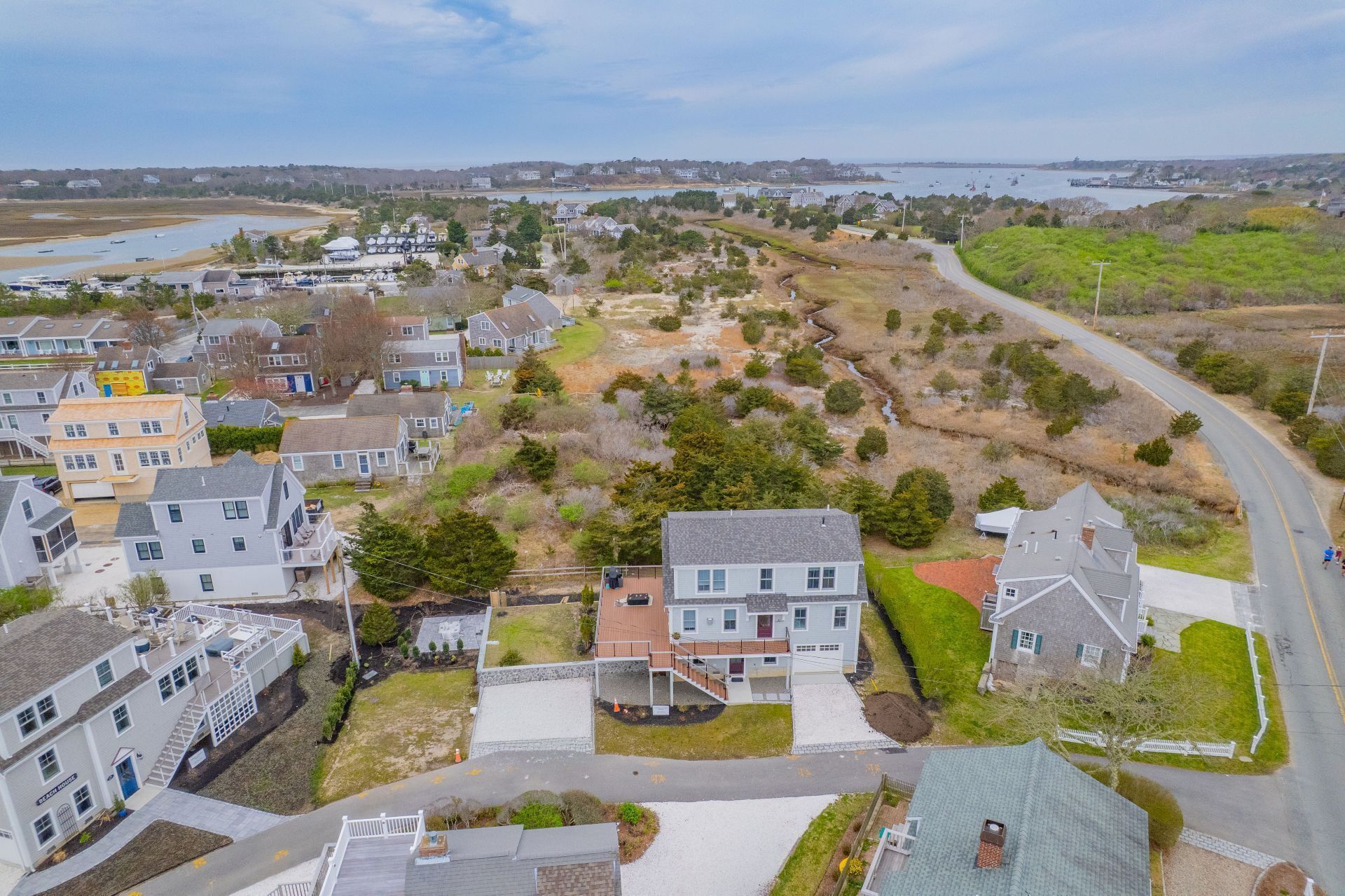Vue aérienne d’un quartier résidentiel avec des maisons, une route et une étendue d’eau en arrière-plan.