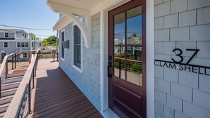 A residential building with a wooden deck and a dark-colored front door. - Slow M'Ocean – A Fresh Take on Cape Calm (Chatham)