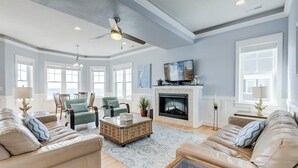 A spacious living room with a fireplace, comfortable seating, and a television. - Over the Moon | Oceanfront | Private Pool and Hot Tub (Virginia Beach)