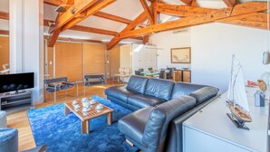 A spacious living area with a leather sofa, a coffee table with cups, and a model sailboat.
