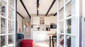 A modern kitchen with white cabinets, a wooden table, and a red ottoman. - Inselkind - Appartement Inselkind (Sylt-Ost)