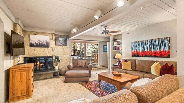 A cozy living room with a fireplace, a sofa set, a wooden cabinet, and a bookshelf. - Stonebridge Condos #717 2 Bedrooms, 2 Baths, 2 Fireplaces (Snowmass Village)