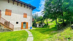 Un bâtiment à deux étages, doté de fondations en pierre, de volets en bois et d’un escalier en pierre menant à l’entrée.