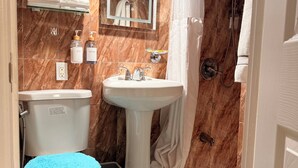 A bathroom with a toilet, sink, shower, marble walls, and a mirror. - 1 bedroom apartment in ground floor very nice and close to everything  (Jamaica)