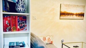 A living room with a sofa, a coffee table, a bookshelf, and a painting on the wall. - 1 bedroom apartment in ground floor very nice and close to everything  (Jamaica)