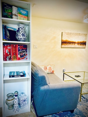 A living room with a sofa, a coffee table, a bookshelf, and a painting on the wall.