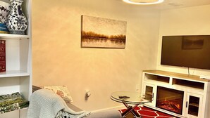A living room with a sofa, a fireplace, a TV, and a bookshelf. - 1 bedroom apartment in ground floor very nice and close to everything  (Jamaica)