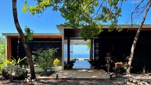 Uma casa moderna com entrada coberta, um caminho até a porta e vista para o oceano.