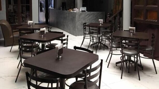 A spacious dining area with multiple tables and chairs, a central bar, and a staircase leading to an upper level.