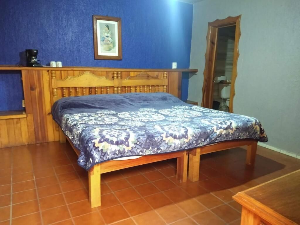 A bedroom with a wooden bed, a blue wall, and a framed picture above the bed.