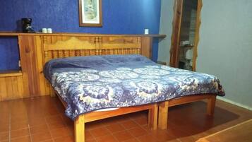 Un dormitorio con una cama de madera, una pared azul y un cuadro enmarcado sobre la cama.