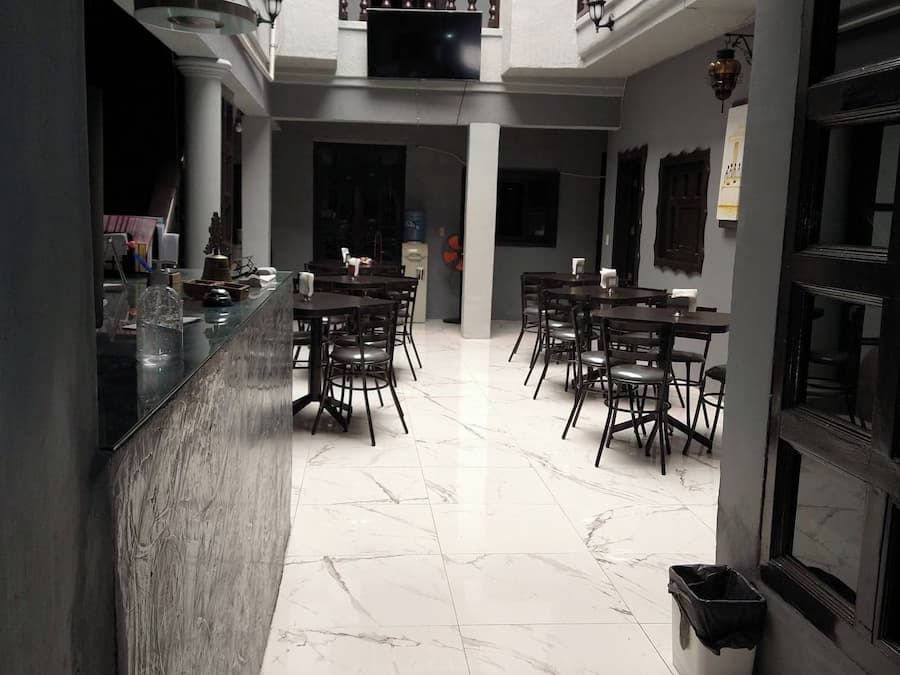Zona interior àmplia amb un espai central obert envoltat de taules i cadires, un dispensador d'aigua i un safata de recollida.
