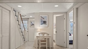 A hallway with a desk and chair, a staircase, and a door leading to a bedroom.