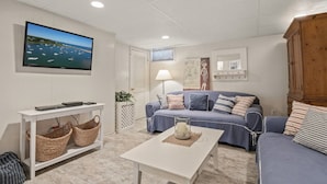 A living room with a television, a sofa, a coffee table, and a white console table with baskets.