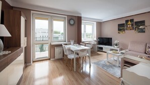 A modern living room with a dining area, a sofa, a TV, and artwork on the wall. - National Stadium Comfy Apartment (Warszawa)