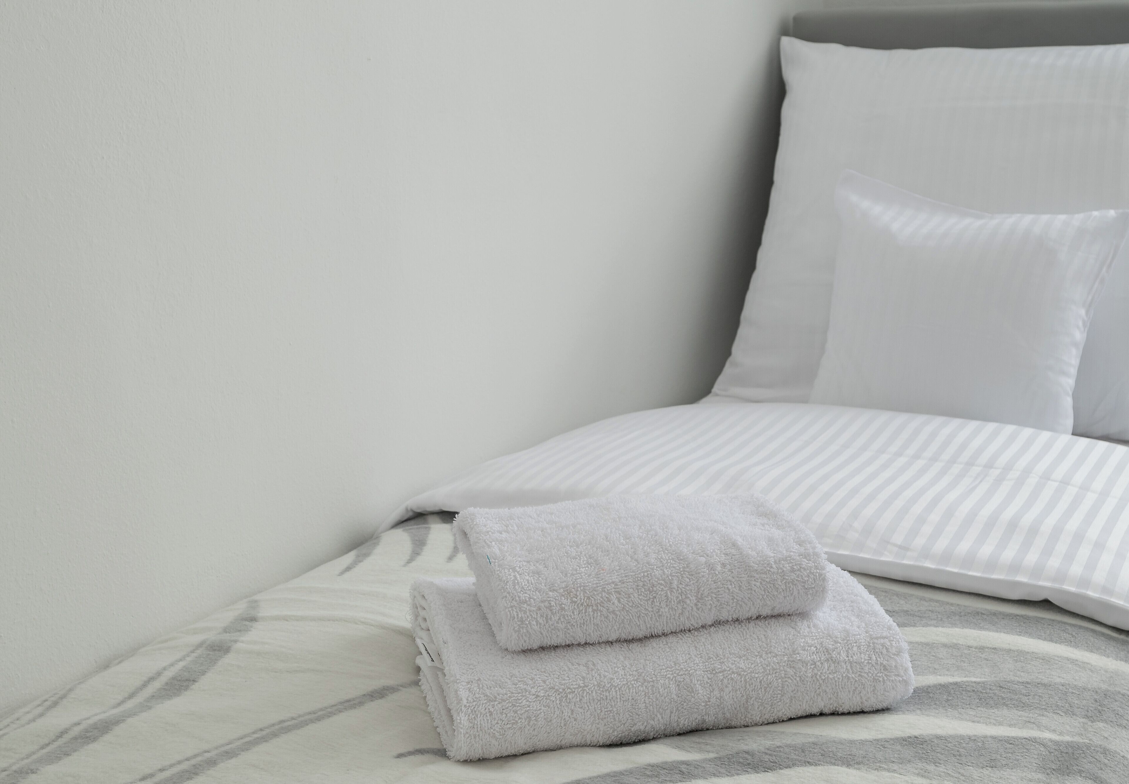 Un lit bien fait, avec une couvre-lit à rayures et deux oreillers.