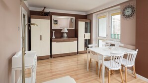 A modern kitchen with white cabinets, a dining table with chairs, and a large window. - National Stadium Comfy Apartment (Warszawa)