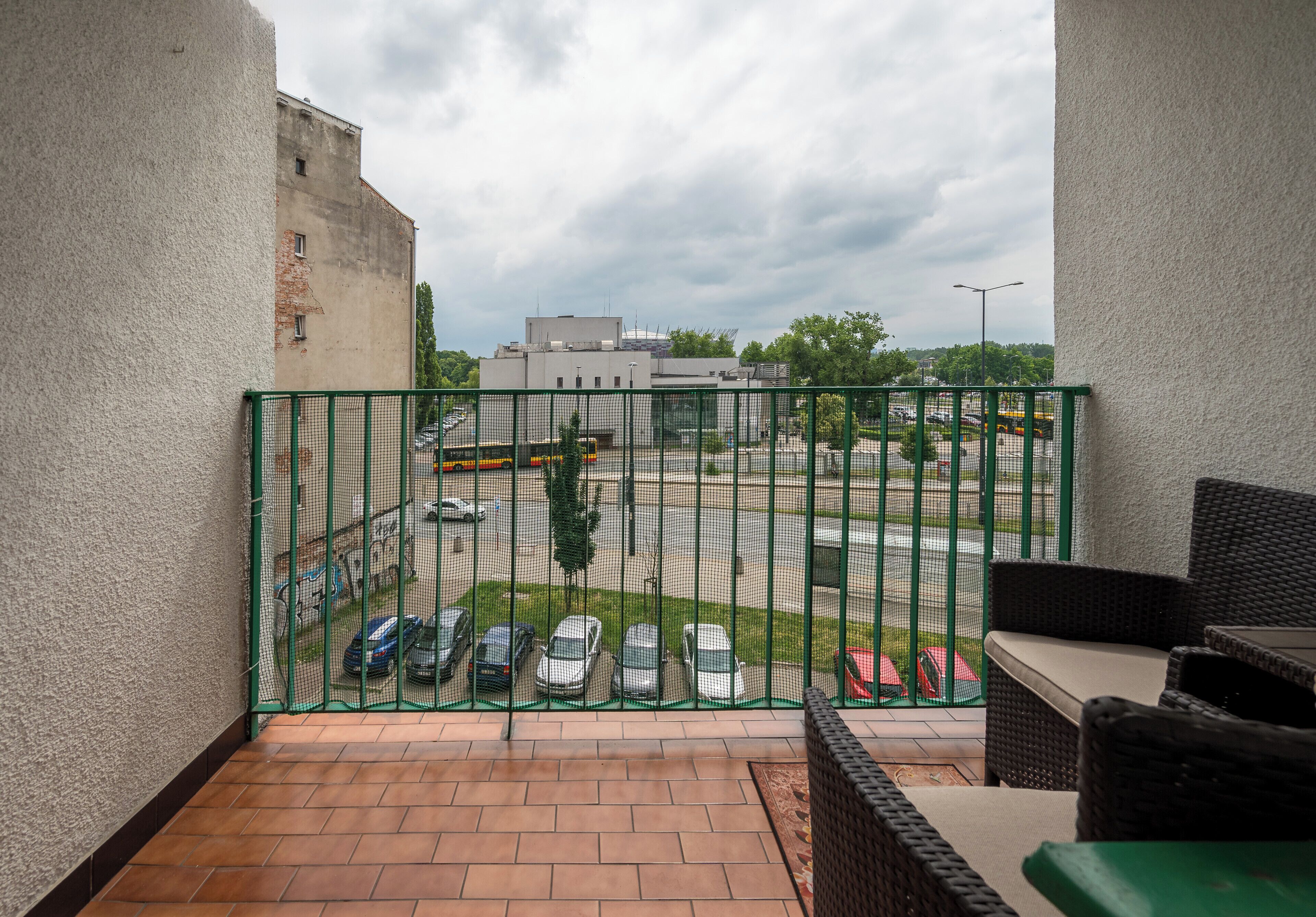 A balcony with a view of a parking lot and buildings.