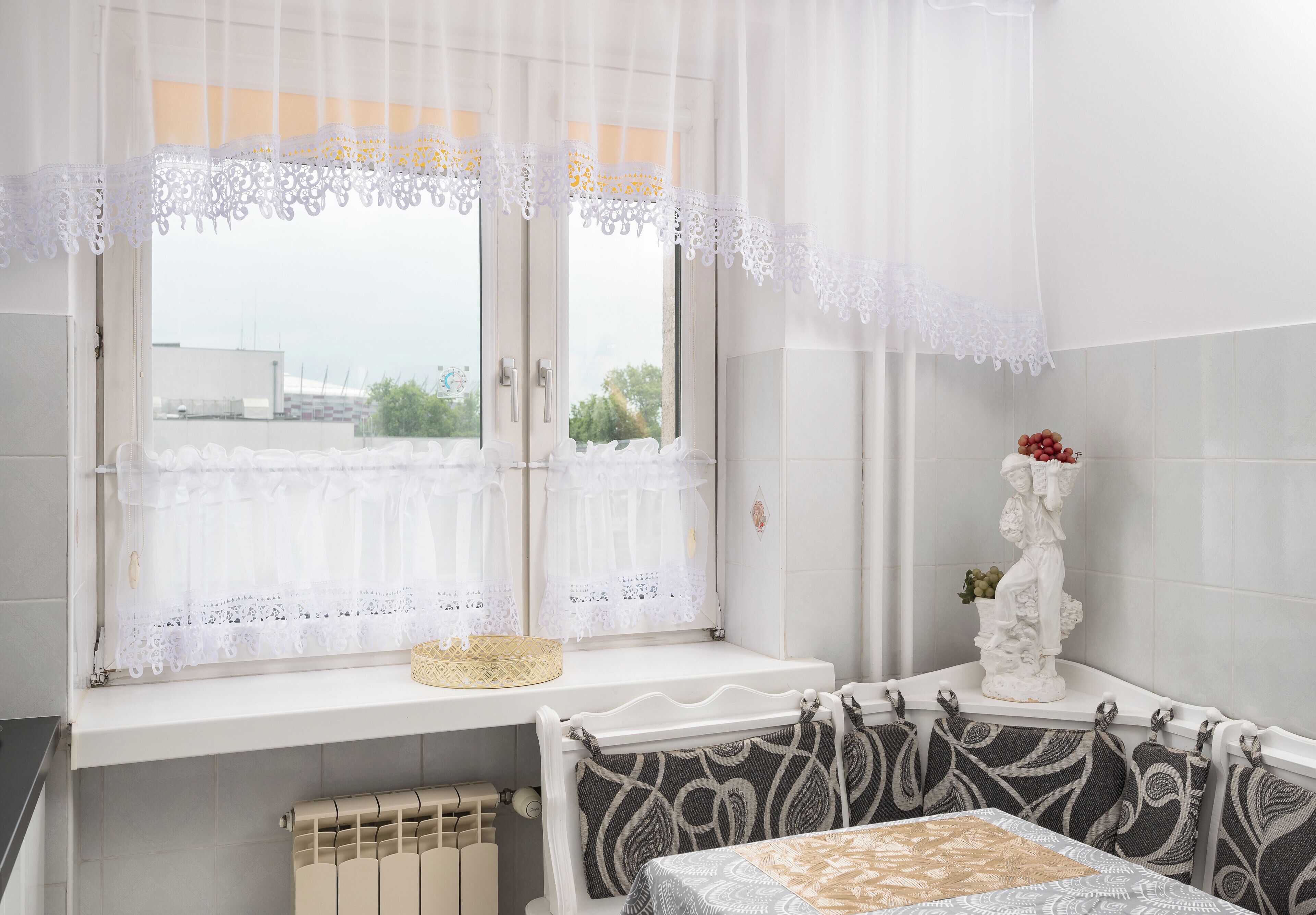 A bathroom with a window, a radiator, a towel rack, and a statue.