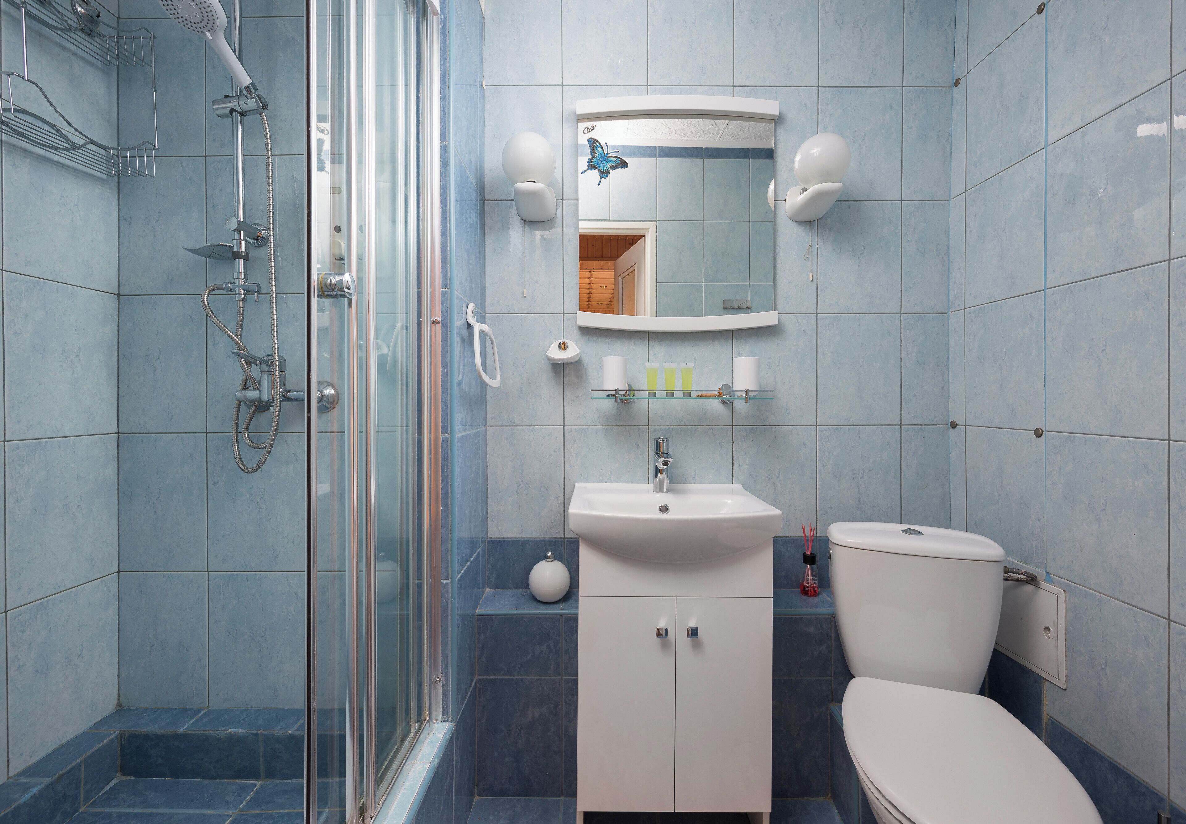 Une salle de bain avec une douche à parois de verre, un lavabo avec un miroir au-dessus et des toilettes.