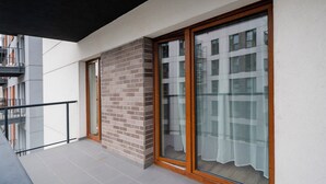 Een modern balkon met een glazen deur, een bakstenen muur en een betegelde vloer.