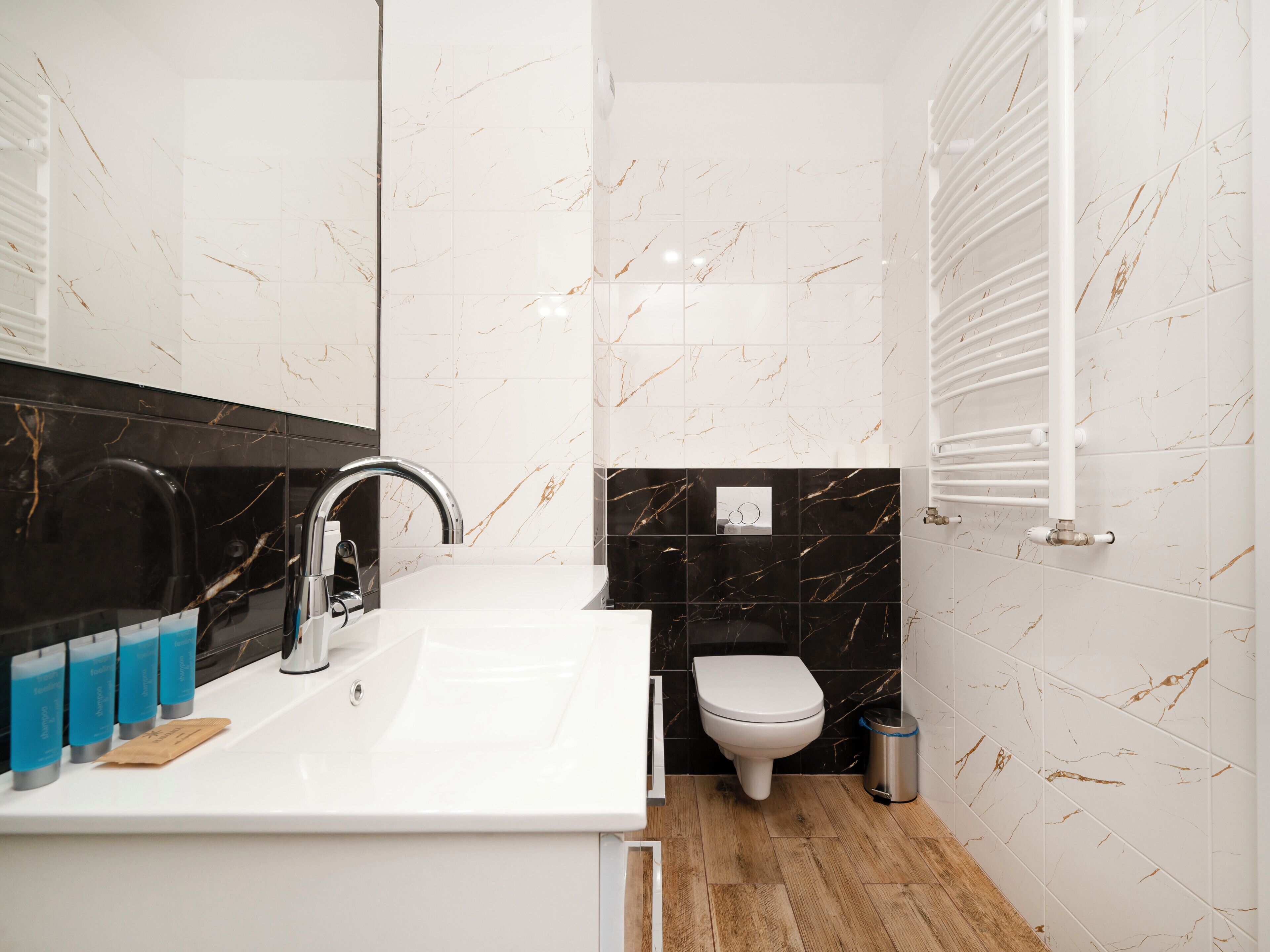 A modern bathroom with a white sink, black marble backsplash, and a white toilet.