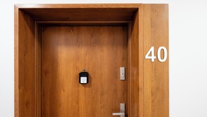 Een houten deur met een numeriek toetsenbordslot, een deurbel en een deurklink.
