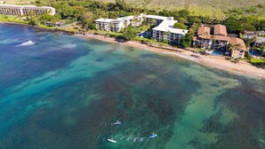 Luftaufnahme eines Küstenresorts mit mehreren Gebäuden, einem Strand und klarem, blauem Wasser.