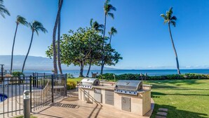Eine Terrasse mit Grill, Pool und Meerblick.