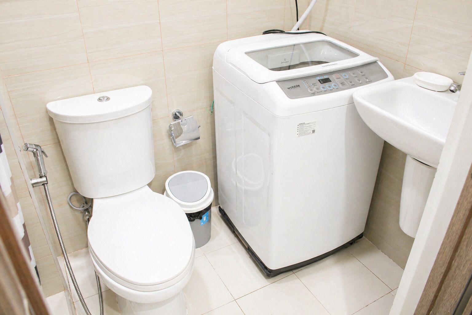 A compact bathroom with a toilet, a washing machine, and a sink.